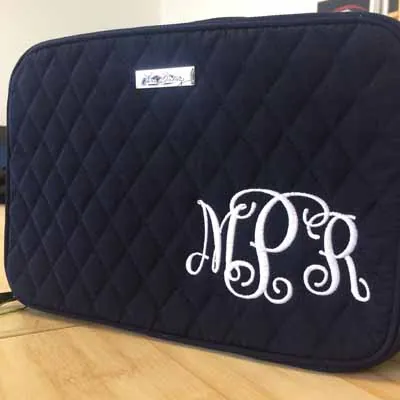 White script monogram embroidered on a navy quilted bag