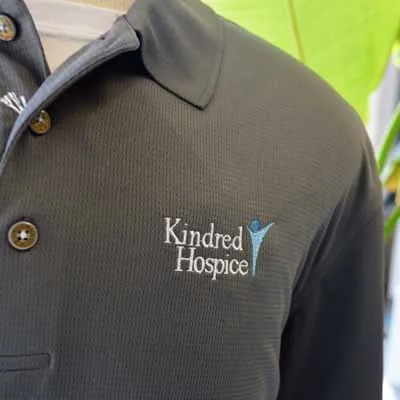 Kindred Hospice logo embroidered on a charcoal polo